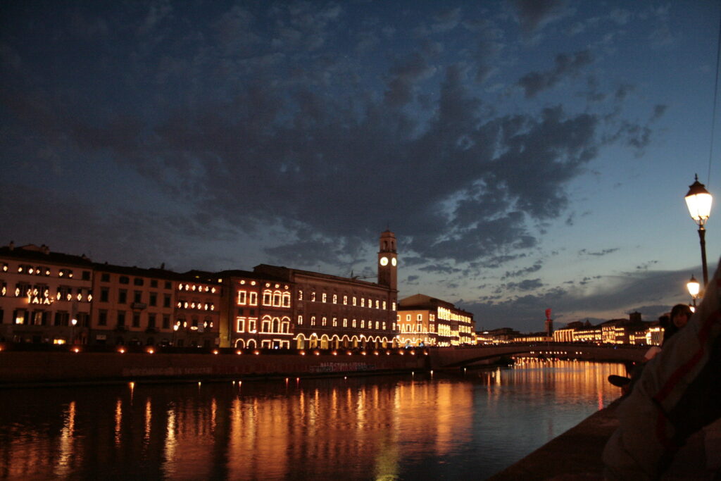 Le sagome dei palazzi che si affacciano sul Lungarno Pisano, illuminati da 100.000 candele, al tramonto.

